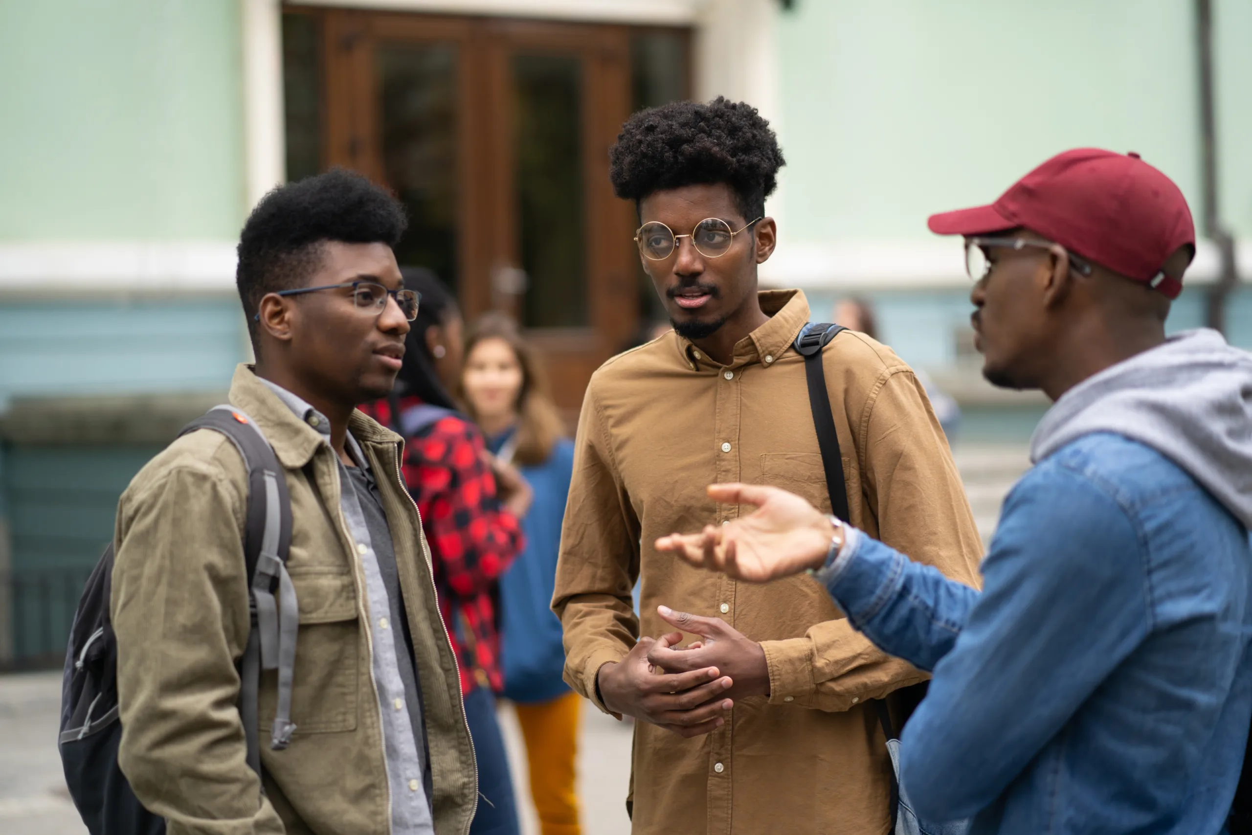 Three African-American students Standing in front of the University and talking, discussing