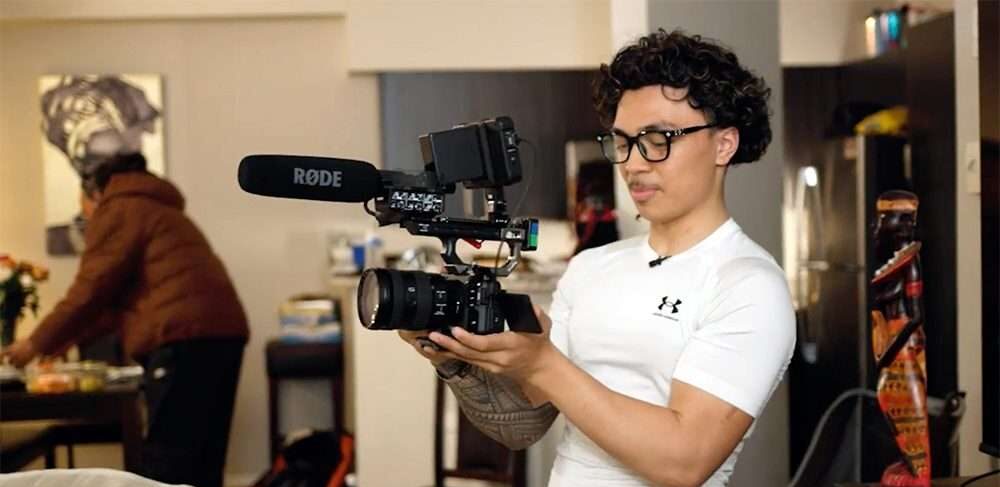 Student holding a camera with a boom microphone.