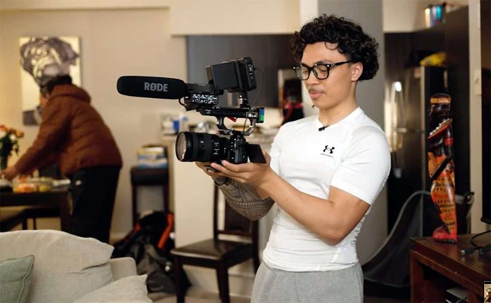 Student holding a camera with a boom microphone.